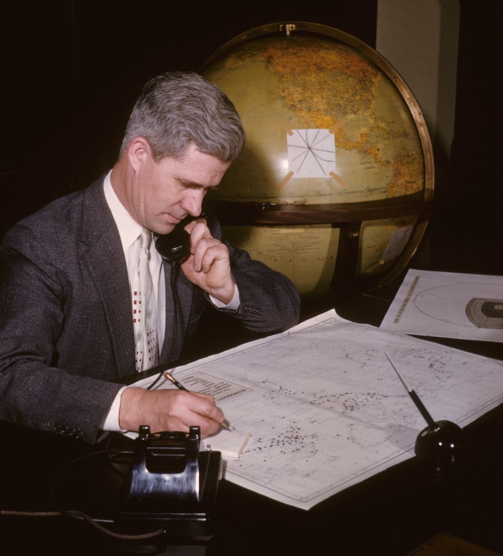 man looking at map in front of globe